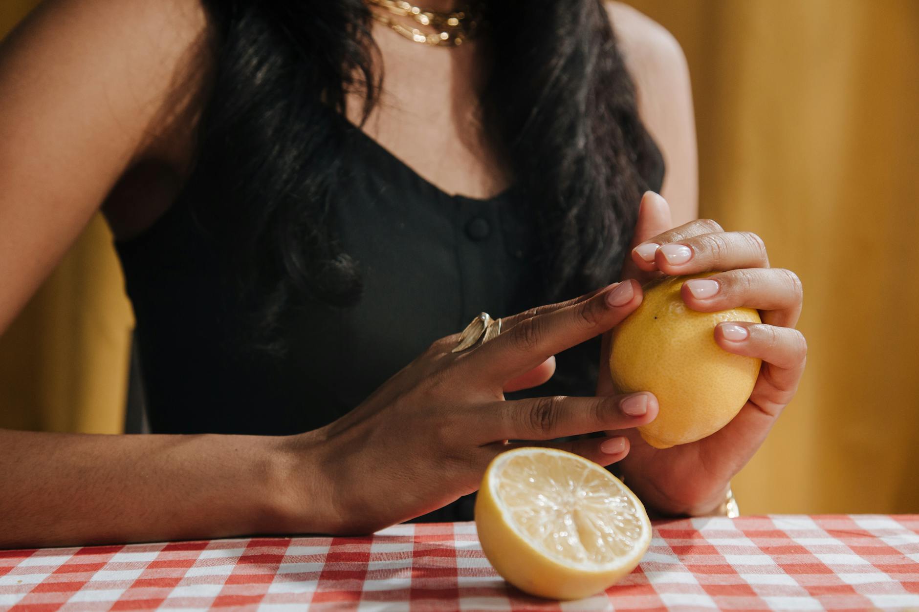 Hand holding a lemon on soft pink background, symbolizing fresh approaches to pleasure