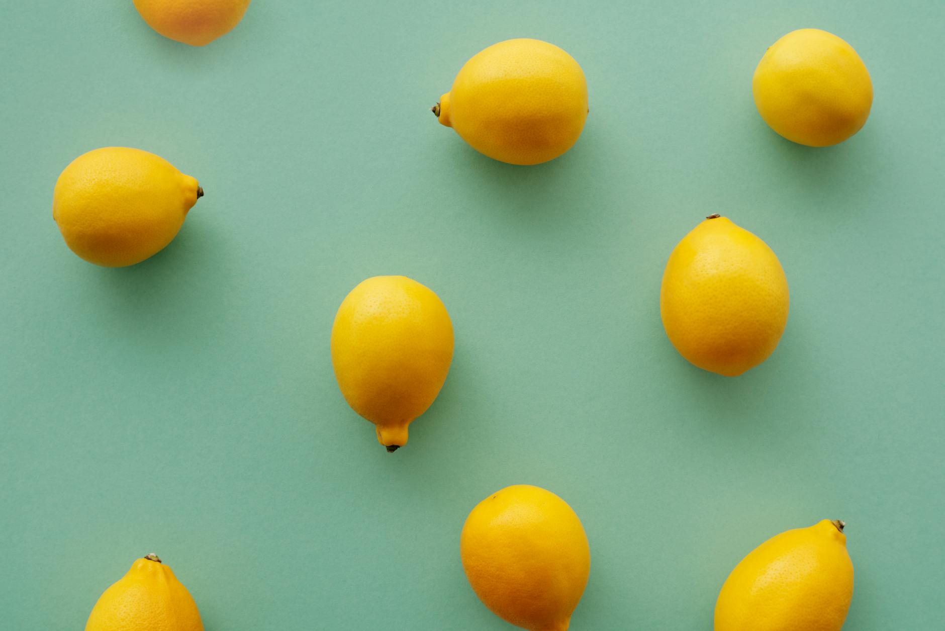 Bright yellow lemons arranged on a pastel green background, symbolizing the refreshing and consistent approach to pleasure with Lem Massager vibrators.