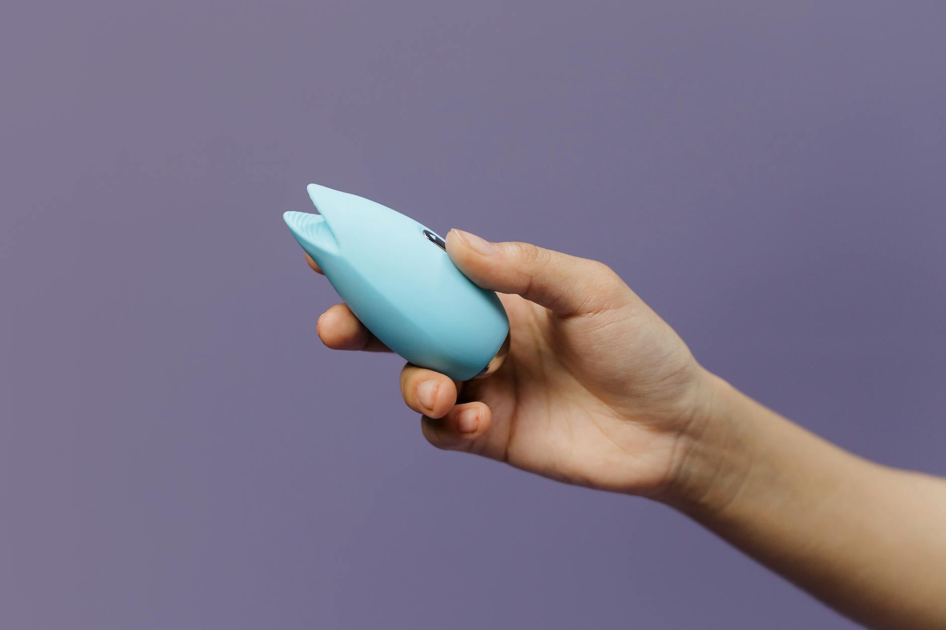 A blue silicone suction vibrator held in hand, representing accessible pleasure technology for partnered intimacy.