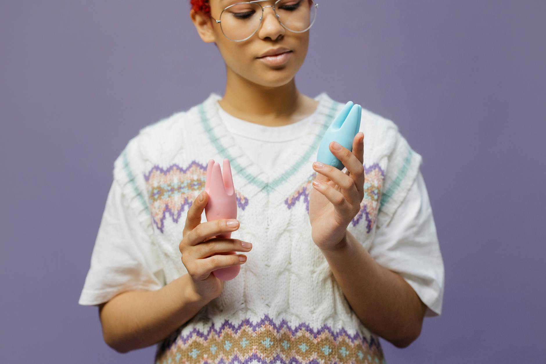 Woman holding colorful silicone vibrators thoughtfully, symbolizing healing and self-connection