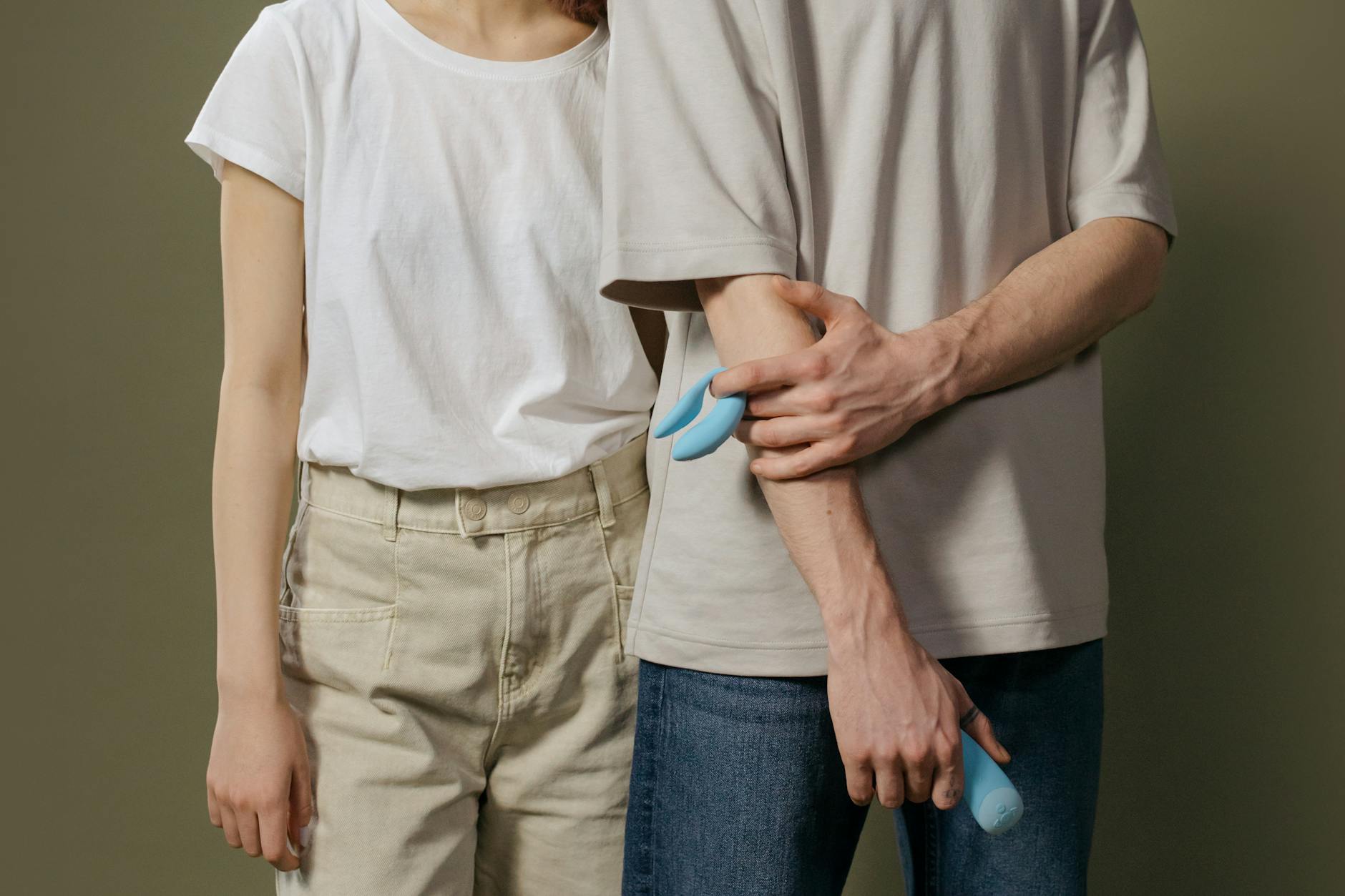 A young couple standing together indoors, holding a lemon vibrator, symbolizing modern intimacy and partnership.