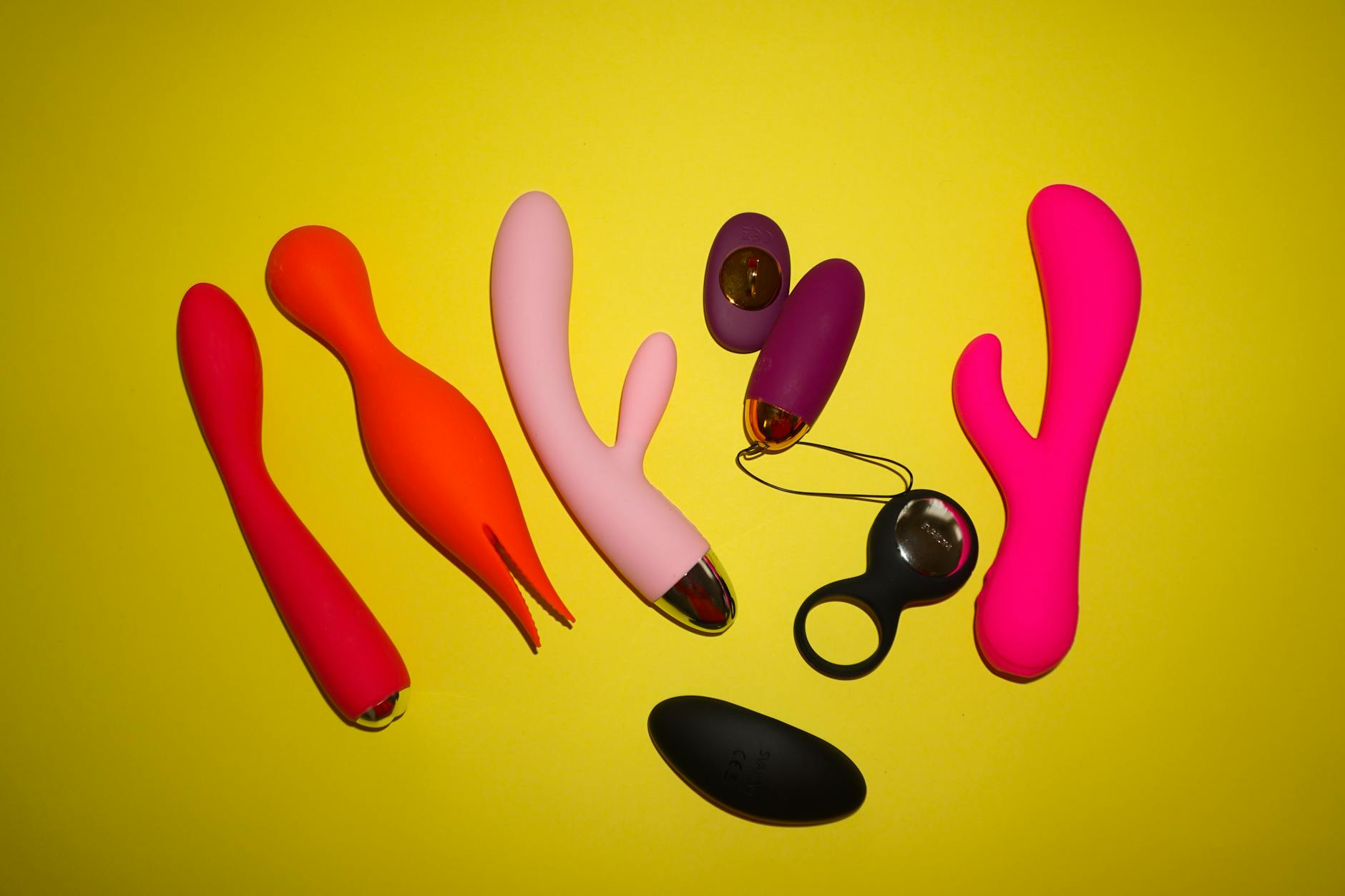 Colorful clitoral vibrators and lemon sexual toys arranged on a bright yellow background